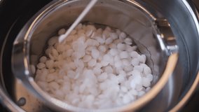 Soy wax flakes are stirred in a container to melt