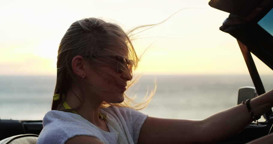 Woman, road trip and happy at sunset at the sea in a car with drive for holiday, adventure and travel outdoor. Transport, wind and ocean with vacation, freedom and nature with a driver in a vehicle