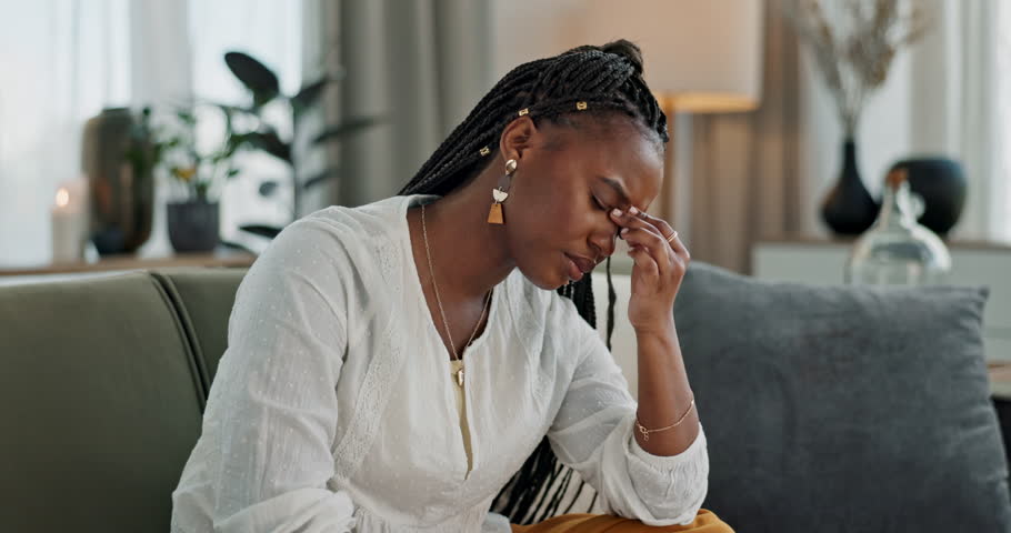 Headache, burnout and young black woman in the living room of her modern apartment on weekend. Stress, mental health and sick African female person with migraine for illness in lounge at home.