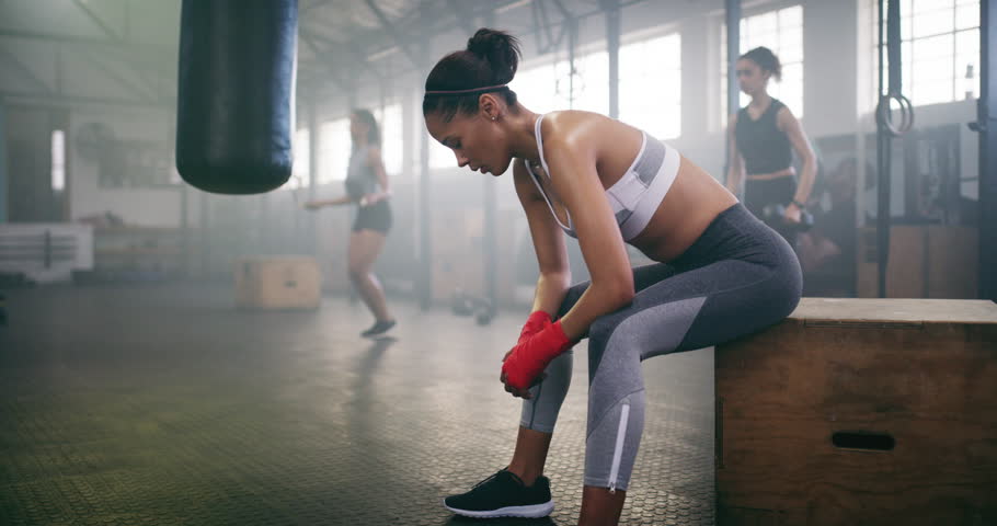 Woman, breathing and tired after boxing in gym for fitness, wellness and fight with punching bag and power. Health, exercise and self defense, recover from sports workout with sweat and boxer athlete Royalty-Free Stock Footage #1110540441