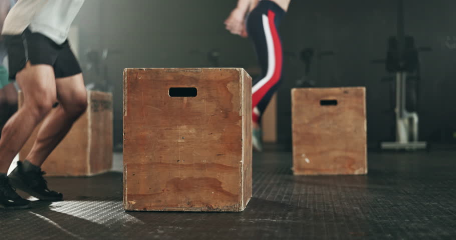 Gym, group and box jump for exercise, workout and cardio performance for muscle, power and action. Closeup legs of strong people training on wooden boxes, fitness class or energy for sports challenge