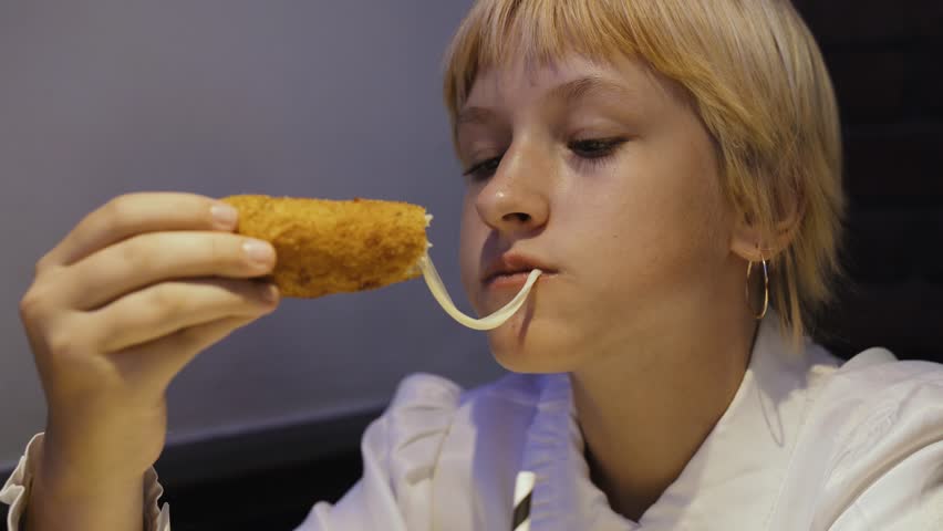 A teenage girl takes with her hands and eats hot cheese sticks with sauce. Close-up. Royalty-Free Stock Footage #1110541993