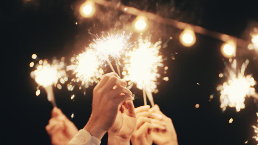 Raised Hands holding burning sparklers at illuminated background. Group of people celebrate merry Christmas together at home party. Happy time at winter new year holiday. Christmas eve night. Friends Royalty-Free Stock Footage #1110544633