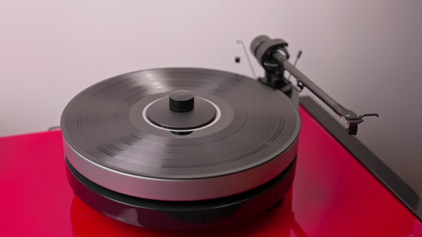 View of person's hands as they turn on high-fidelity vinyl record player and lower tonearm onto vinyl to start listening to music. | Shutterstock HD Video #1110547921
