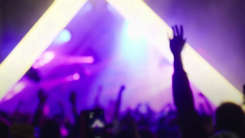 Happy people watching amazing musical concert. Bright colorful stage lighting. Nightlife and entertainment concept. People with raised arms on music event with lights. 4K, UHD Royalty-Free Stock Footage #1110549491