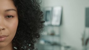 People close up half face portrait of calm relaxed young multi racial curly model. Pretty mixed race girl no facial expression looking straight to camera in modern apartment on blurred copy background - Powered by Shutterstock - Get 15% off with code: PIKWIZARD15