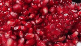 Super close-up of red pomegranate grains falling in slow motion on the background of pomegranate texture. High quality FullHD footage