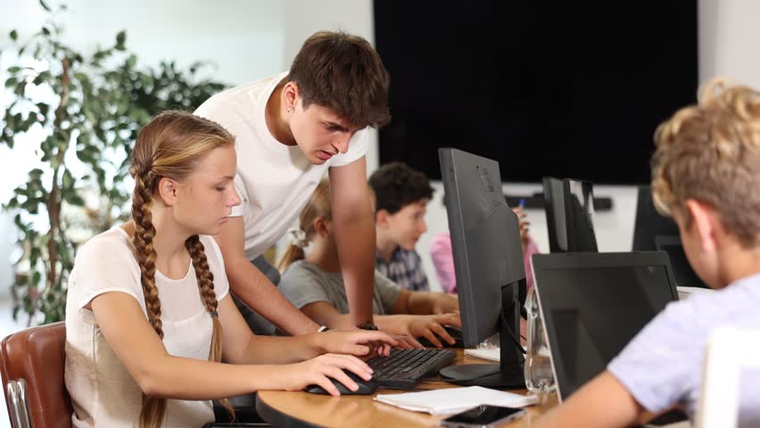 Concerned preteen girl sitting at computer while trainer explaining him something during IT courses  Royalty-Free Stock Footage #1110555971