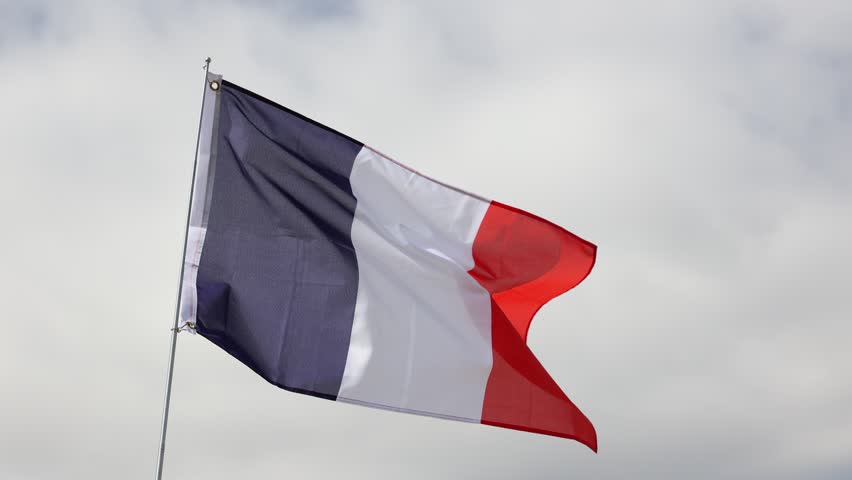 Vibrant blue, white and red French tricolour symbolizing freedom, equality and fraternity waving on flagpole against cloudy sky on sunny day. Concept of national pride, traditions, history and culture