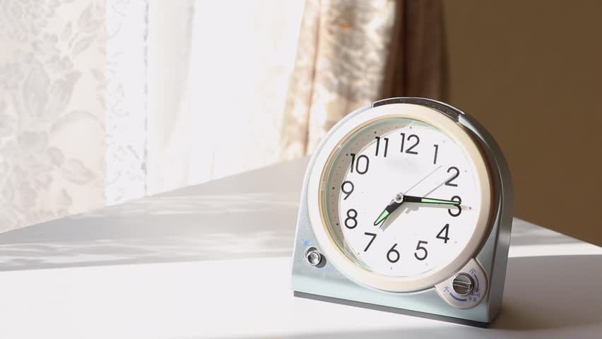 A table clock on a desk by the window in the morning Royalty-Free Stock Footage #1110559689