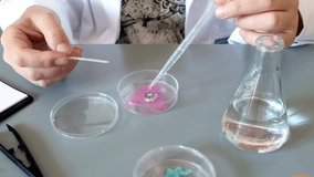 Unrecognizable female scientist hands pouring liquid from pipette over pink glitter sample on a petri dish in environment research lab. Woman chemist studying microplastics on cosmetic composition. - Powered by Shutterstock - Get 15% off with code: PIKWIZARD15