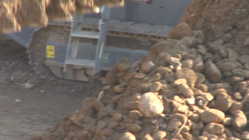Bulldozer unloading soil and stone at construction site