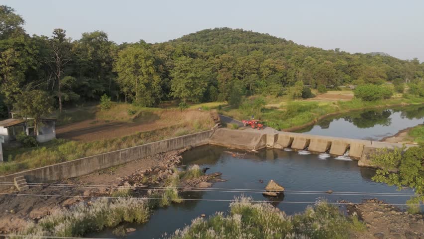 Aerial view of river in forest with the Check dam and tractor trailer.