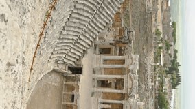 Vertical video. Wide Angle, Panorama of the Ancient Amphitheater, people below on the steps admiring and photographing the Ancient Art.
