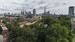 Aerial View Shot of London UK, United Kingdom, day, Square Mile, London Skyline, City of London, Shard, wide establishing, low push over trees