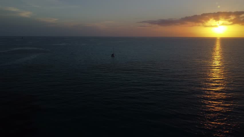 The aerial drone footage of a boat at sunset. Long Bay beach, San Salvador Island, Bahamas.