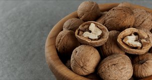 Wooden bowl with walnuts on a gray background. Close-up footage on the rotating table.