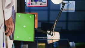 Vertical video Middle Eastern man scrolling on green screen laptop, checking social media posts. Self employed man browsing online websites from mockup device in apartment office with TV as background - Powered by Shutterstock - Get 15% off with code: PIKWIZARD15