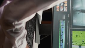 Vertical video Arabic cinematographer editing new project, creating film montage, working with footage and sound. Man using post production software to process movie on computer workstation