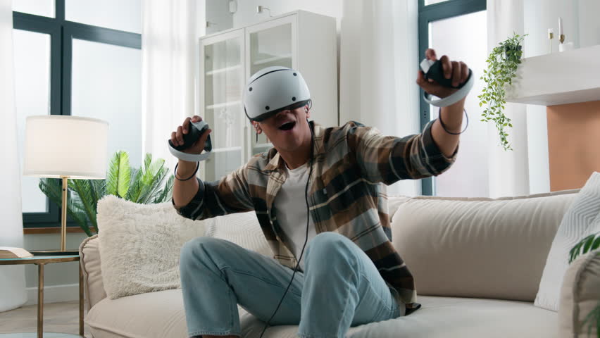 Metaverse virtual reality experience in cyberspace world happy amazed African American man having fun play game playing guy meta universe VR goggles helmet cyber gamer at home futuristic space gaming