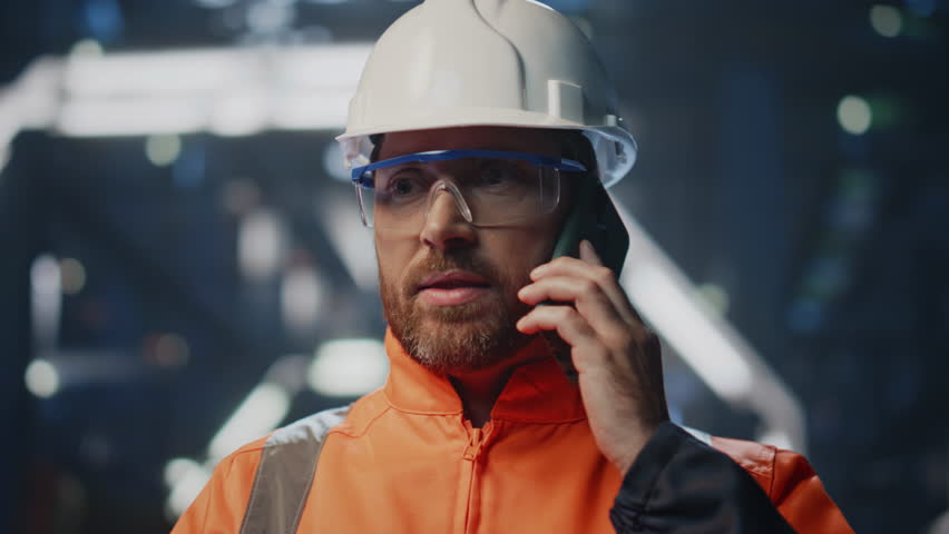 Factory technical specialist calling phone complaining on workshop equipment closeup. Portrait of worried engineer talking smartphone nervously. Uniformed production worker quarrelling by cellphone. Royalty-Free Stock Footage #1110577003