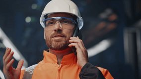 Smiling industrial engineer speaking cellphone making deal on metallurgy factory close up. Happy hardware enterprise owner talking smartphone. Bearded uniformed mechanic have mobile phone conversation - Powered by Shutterstock - Get 15% off with code: PIKWIZARD15