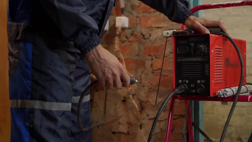 Close up shot of professional welder starts welding machine. Worker wearing protective suit begins working process at construction site. Royalty-Free Stock Footage #1110578339