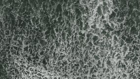 Aerial top down view of foam waves rolling into sand ocean beach. Concept of beautiful and powerful nature.