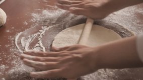 Slow motion footage of a person preparing dough for a pizza