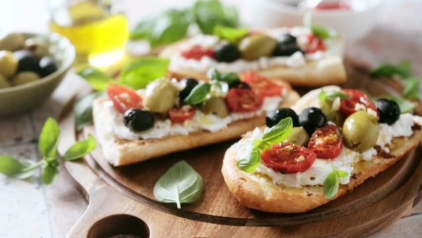 Sandwiches with bruschetta or toasts, cream cheese, baked tomatoes and marinated olives. Antipasti bruschetta, Mediterranean food appetizer. Stock video 4k Royalty-Free Stock Footage #1110587119