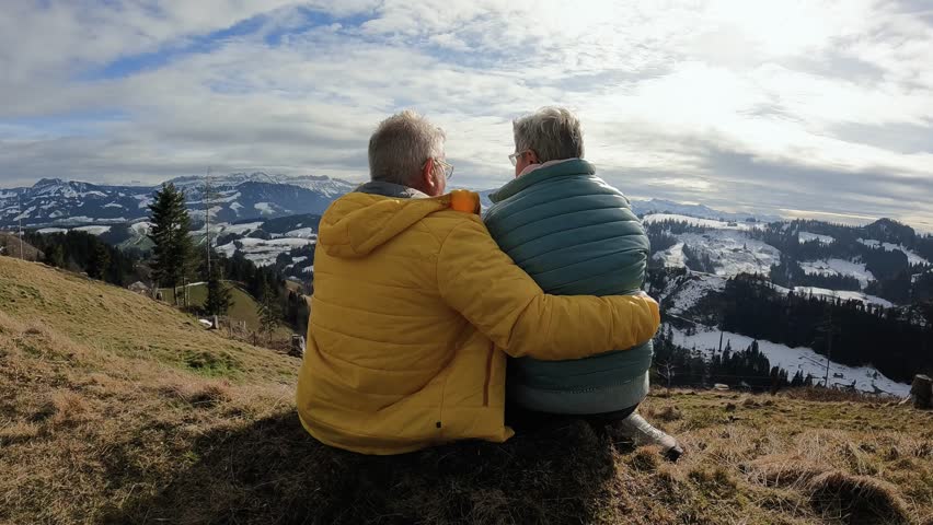 Back view of senior couple hugging each other while resting and enjoy landscape at mountain peak during hiking winter day Royalty-Free Stock Footage #1110592315