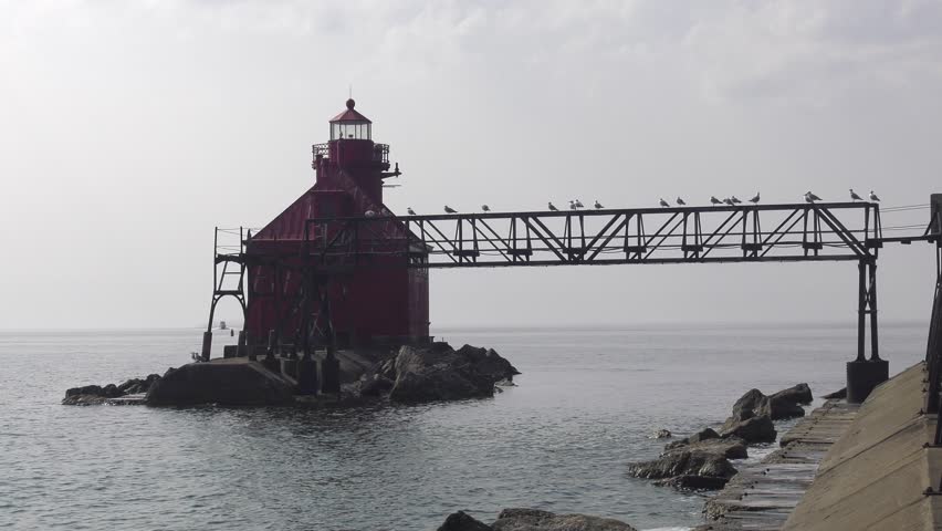 Sturgeon Bay lighthouse on Lake Michigan. Closeup shot of the lighthouse and the aerial catwalk with numerous gulls perched on it. Shot on a very overcast day as Canadian wildfire smoke moves in.
