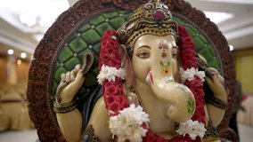 Lord Ganesha idol decorated with garland and flowers.