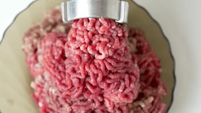 Beef mince in a mincing machine, close up. The meat industry, the process of cooking minced beef in electric grinder, 4k slow motion