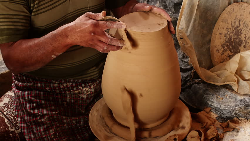Man potter creating big ceramic vase in workshop on pottery wheel, hands close-up. Master shaping raw pitcher jug workpiece cutting clay excess with spatula. Ceramic business, making clay products.  Royalty-Free Stock Footage #1110600885