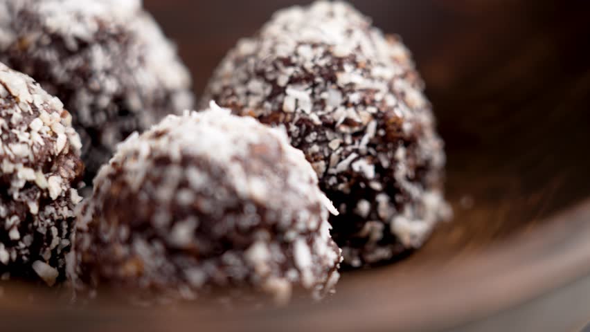 Chocolate coco balls in dark wooden bowl. Rotation. Macro shot