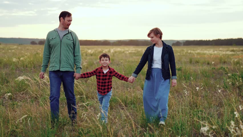 Family of parents and child walks on weekend in countryside in cloudy weather