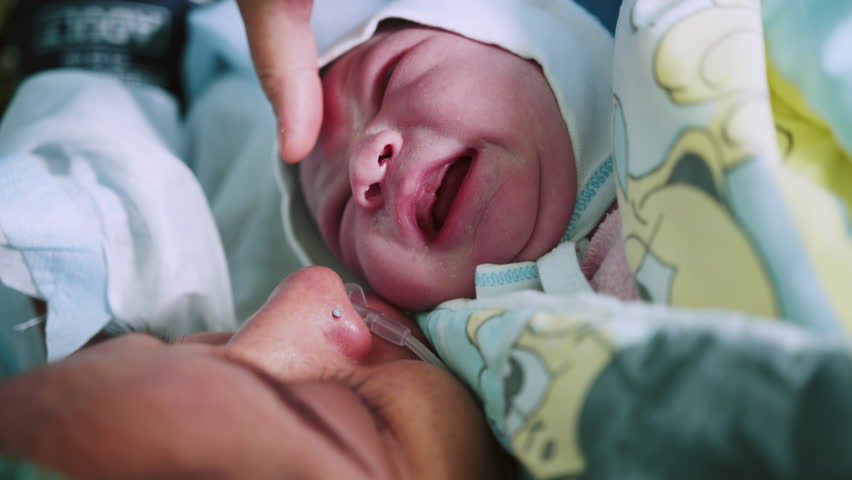 Mother Holds Newborn Baby in Hospital. Mother Holding Her Newborn Baby on Her Chest Just After Delivery. First Sight of Mom and Her Newborn in Operation Room. Modern Hospital Operation Room Royalty-Free Stock Footage #1110603649