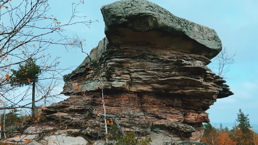 Stone City in autumn. Bright foliage and autumn landscape. The natural landscape is a rock formation in Central Russia, the Urals. A natural monument. Ancient rocky folding in the Ural Mountains. 4K