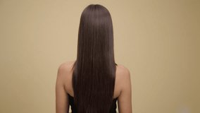 Luxurious long brunette hair. Back view. Yellow background.