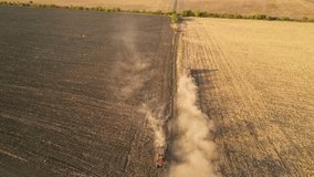 High angle flyover drone shot of tractor plowing a field in autumn. Golden yellow sunset top down footage of farming in a rural area. 4k quadcopter video of farming machines.