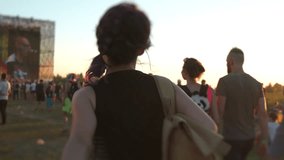 Rear view of Asian teenage woman dancing among the crowd of people at rock open air concert festival. Girl moving to stage. Music fans enjoying summer gig. Concept of youth culture and entertainment. - Powered by Shutterstock - Get 15% off with code: PIKWIZARD15