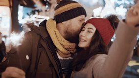 Multiracial couple have fun kiss with sparklers outdoor celebrating merry Christmas xmas and happy new year. Young man woman on date smiling waving firework express joy happiness. Christmas holiday - Powered by Shutterstock - Get 15% off with code: PIKWIZARD15