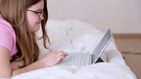 Focused teenager in glasses taking foreign languages courses via tablet blonde girl lying on bed at home studying English online using modern electronic device - Powered by Shutterstock - Get 15% off with code: PIKWIZARD15