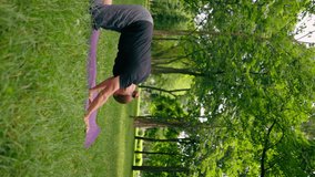 vertical video handsome bearded man meditating in the park practicing yoga doing stretching and exercises different muscle groups