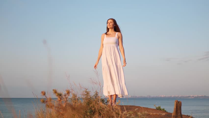 Beautiful woman enjoying sunrise near sea at summer