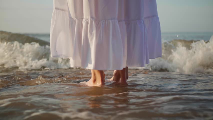 Woman standing in water and enjoying sea at sunrise, closeup