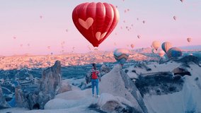 Heart shape hot air balloon. Female traveller looks on hot air balloons at Cappadocia, Turkey. 14 February concept video.
