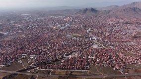 Person paragliding over eastern european town. Aerial drone video of Prilep in North Macedonia.