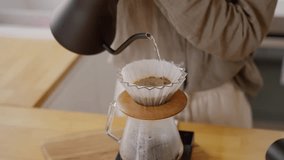 Close up pouring water from black kettle in v60 paper filter with fresh grind coffee beans on the wooden table in kitchen at home - Powered by Shutterstock - Get 15% off with code: PIKWIZARD15